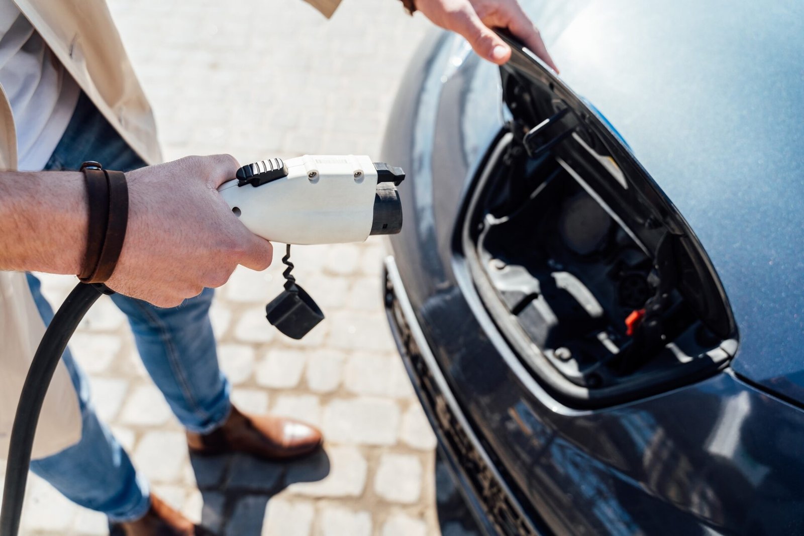 L'homme inserte le bouchon du chargeur dans la prise de gros plan de voiture électrique
