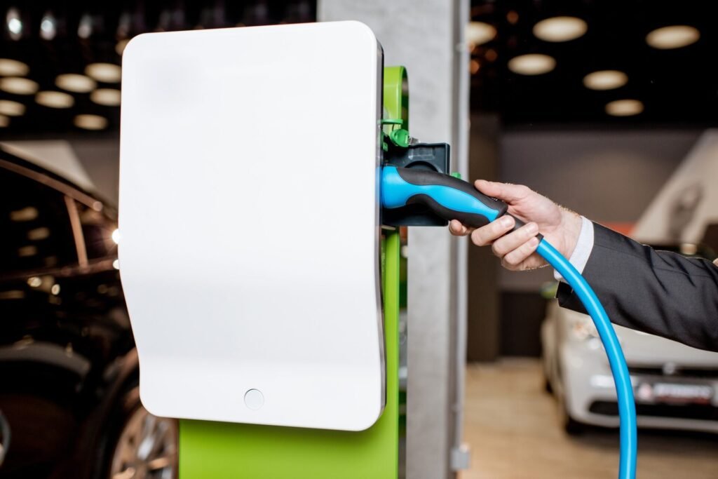 Câble de bouchage de l'homme dans la station de charge pour les voitures électriques chez le concessionnaire automobile, vue grossière