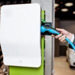 Câble de bouchage de l'homme dans la station de charge pour les voitures électriques chez le concessionnaire automobile, vue grossière