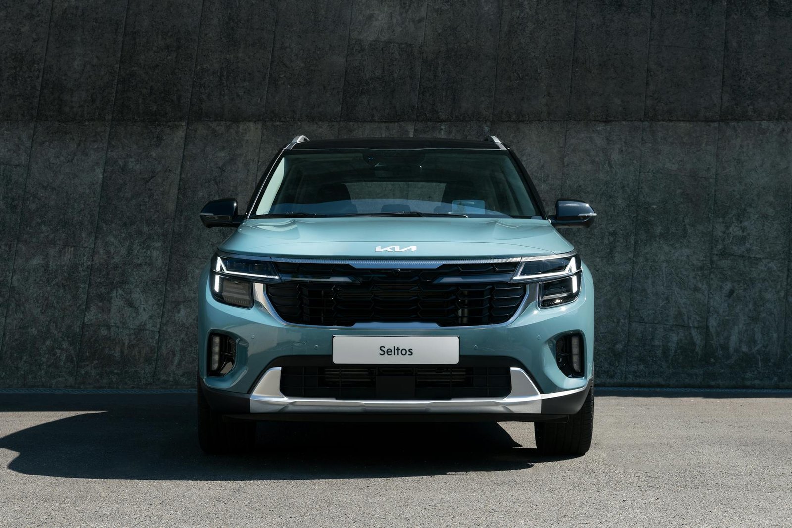 Un SUV Blue Kia Seltos moderne s'est garé contre un mur de béton en plein jour.