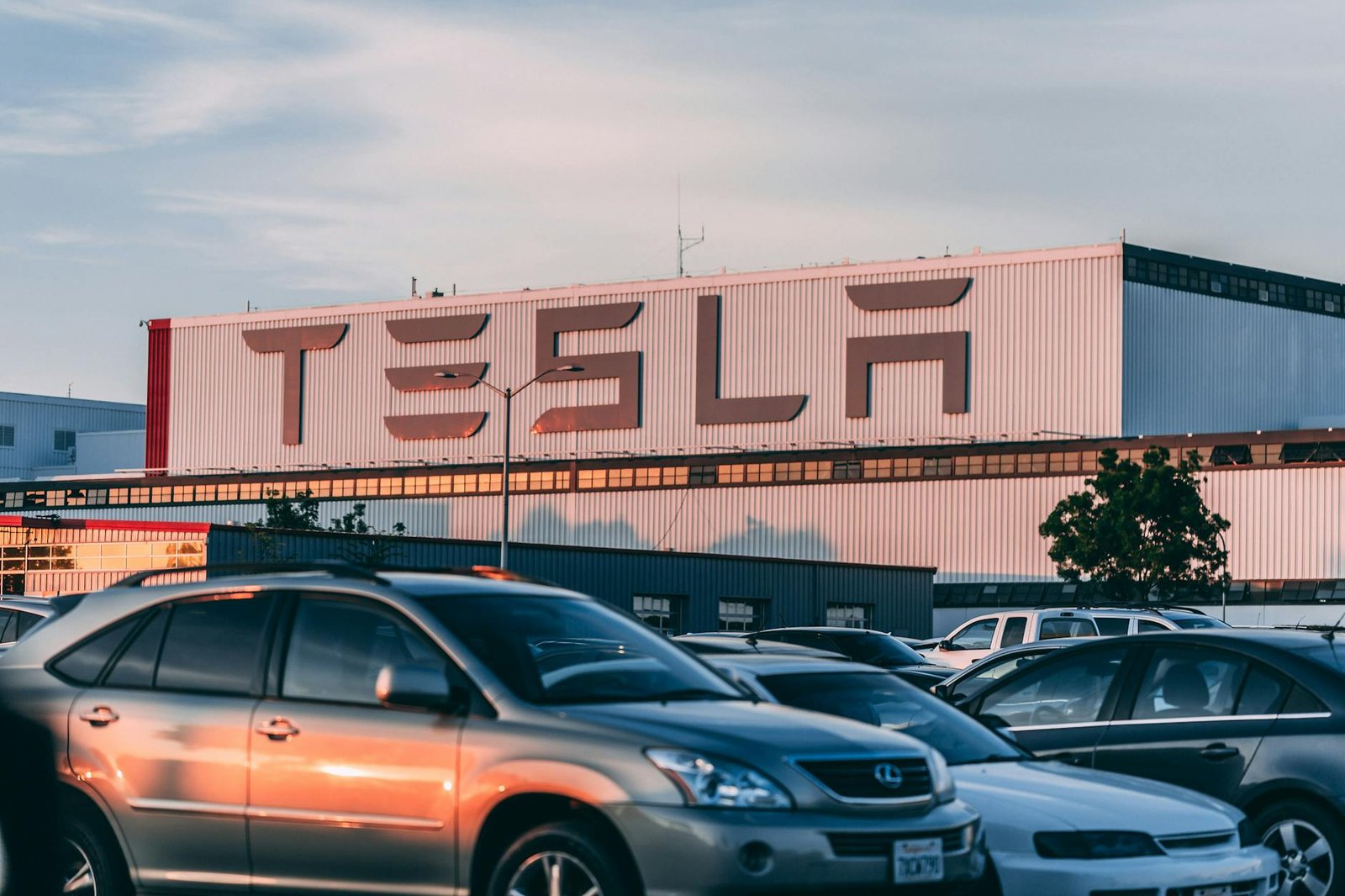 L'usine Tesla avec des voitures garées pendant le coucher du soleil, présentant des vibrations modernes de l'industrie automobile.