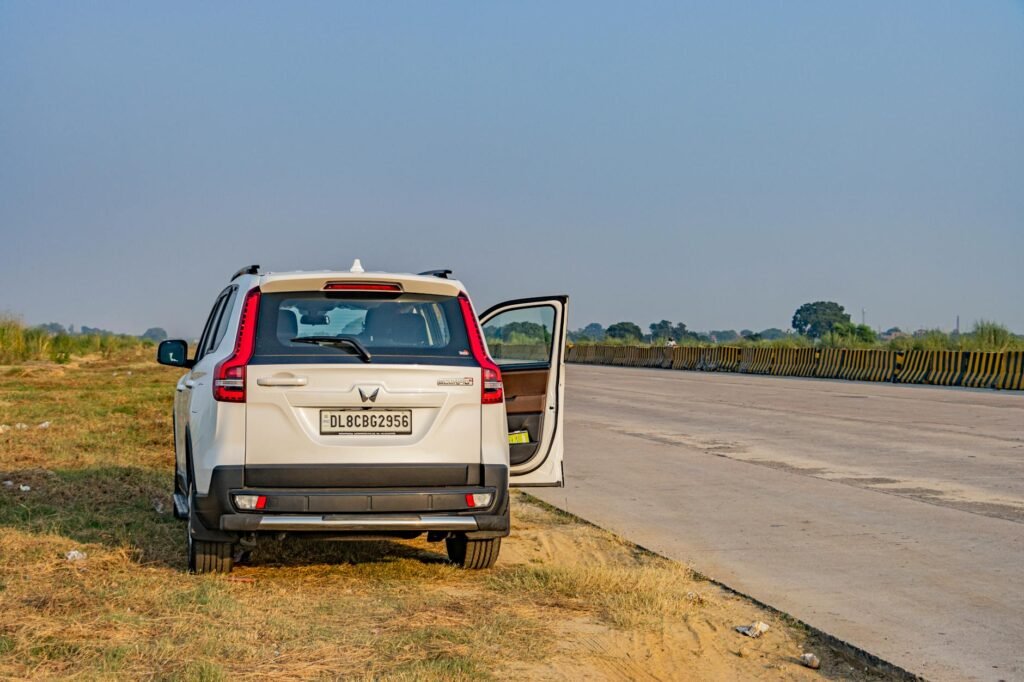 Un SUV blanc s'est garé sur une autoroute indienne déserte pendant la journée, capturant la vaste route ouverte et le paysage.