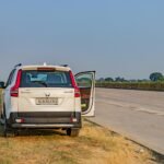 Un SUV blanc s'est garé sur une autoroute indienne déserte pendant la journée, capturant la vaste route ouverte et le paysage.