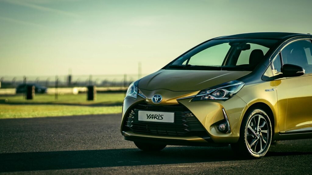 Toyota Yaris jaune élégante s'est garée sur une route d'asphalte ensoleillée à l'extérieur.
