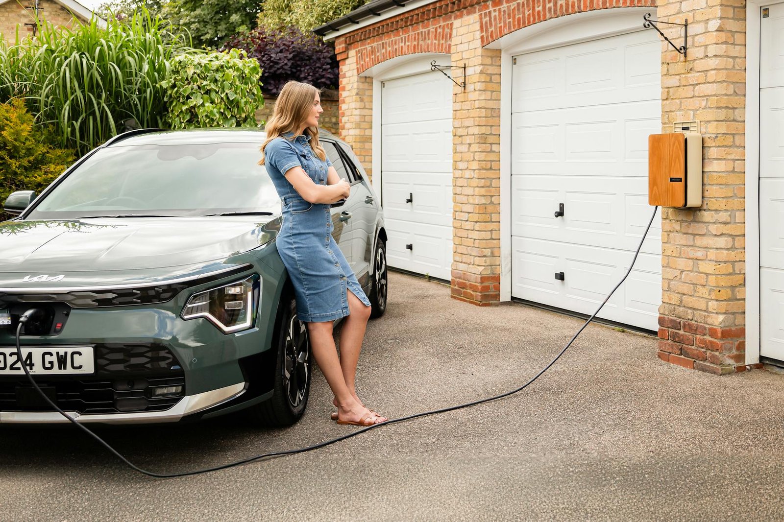 Femme facturant un véhicule électrique à la maison avec une station de charge moderne murale.