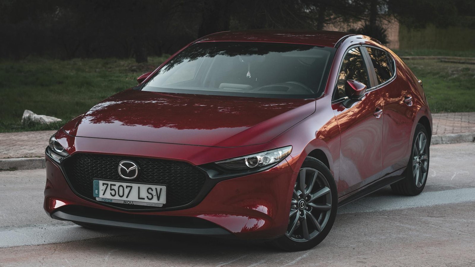 Élégante Mazda 3 rouge garée à l'extérieur, présentant un design élégant et moderne.