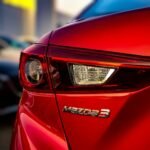 Superbe gros plan du feu arrière d'une Mazda 3 rouge présentant un design élégant et des couleurs vives.